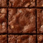 Keto Almond Flour Brownies: Fudgy keto almond flour brownies with a glossy crackly top and dense, moist interior on a simple background.