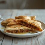 Arayes Stuffed Pita: Crispy golden Arayes Stuffed Pita with spiced lamb and fresh herbs on a plate.