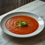 Cold Gazpacho Andaluz: Cold Gazpacho Andaluz in a white bowl with fresh tomatoes and olive oil garnish.