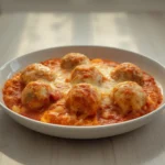 Keto Meatball Sub Casserole: Golden cheesy keto meatball sub casserole bubbling in a dish with savory sauce and meatballs visible.