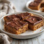Keto Peanut Butter Bars: No-bake keto peanut butter bars with glistening chocolate top and golden edges on a clean surface.