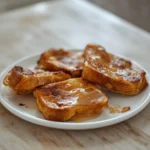 Low Carb French Toast: Golden, caramel-brown low carb french toast slices glistening on a plate with crisp edges.