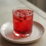 Pomegranate Spritz: Ruby-red pomegranate spritz in a glass with bubbles and arils, looking refreshing and detoxifying.