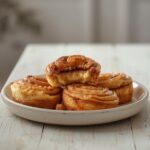 Keto Cinnamon Roll Bites: Golden keto cinnamon roll bites with caramel-brown glaze and creamy cinnamon filling on a baking sheet.
