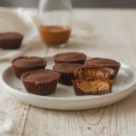 Keto Peanut Butter Cups: Easy keto peanut butter cups with melted chocolate and creamy filling on a white plate.