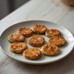 Low Carb Fried Zucchini: Golden crispy low carb fried zucchini bites on a plate with a light, toasted coating.
