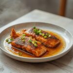 Soy Ginger Salmon: Glistening glazed soy ginger salmon fillets in a skillet with fresh green onions