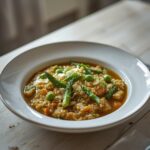 Spring Vegetable Farro Risotto: Creamy Spring Vegetable Farro Risotto in a white bowl with asparagus, peas, and zucchini, glistening with olive oil and parmesan.