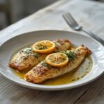 Baked Mediterranean Sea Bream: Golden baked Mediterranean sea bream fillets with lemon slices and herbs on a baking sheet.