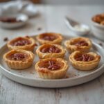 Low Carb Nut Tartlets: Golden low carb nut tartlets with flaky almond crusts and creamy filling on a rustic wooden board.