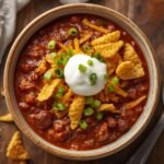 A rustic white bowl filled with a delicious, hearty Easy Crockpot Chili Recipe garnished with toppings.